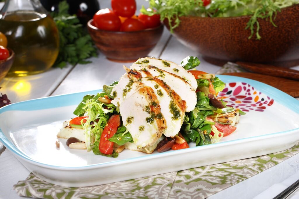 Grilled chicken salad served with fresh, colourful vegetables on a plate.